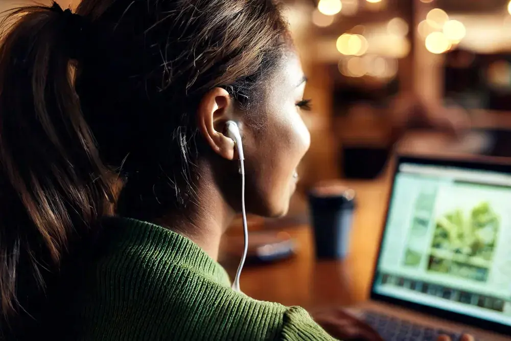 Text-to-speech. A woman wearing earphones and using a laptop